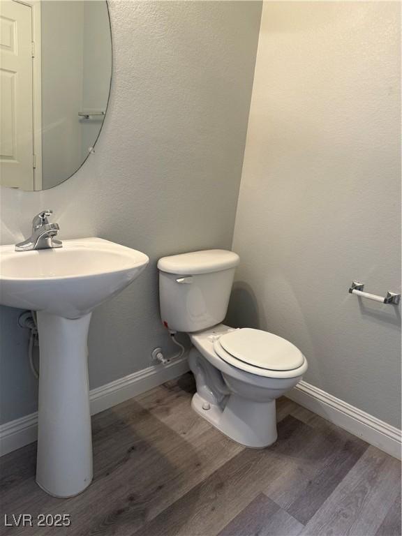 258 Bella Matese Ave, Las Vegas, NV 89183 - bathroom with wood finished floors, toilet, baseboards, and a sink