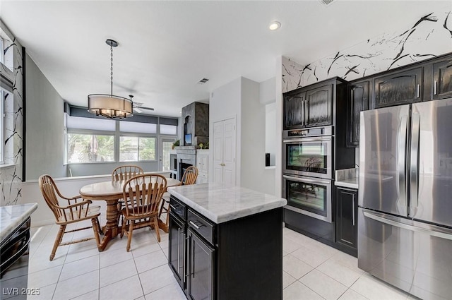 9220 Evergreen Canyon Dr, Las Vegas, NV 89134 - kitchen featuring appliances with stainless steel finishes, a fireplace, light tile patterned floors, light stone counters, and recessed lighting