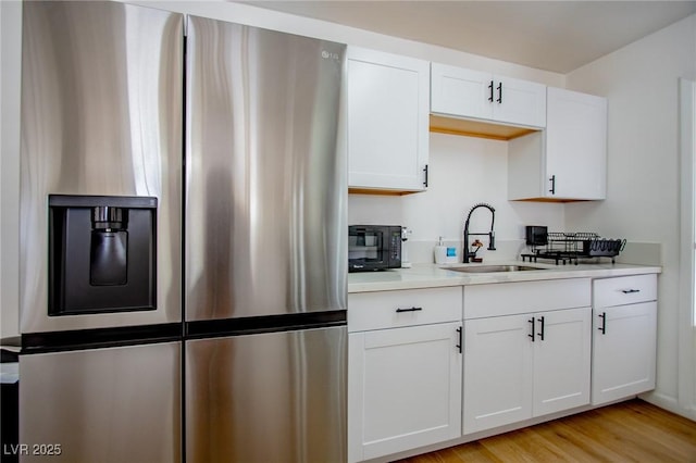 6301 Garwood Ave, Las Vegas, NV 89107 - kitchen with stainless steel refrigerator with ice dispenser, a sink, light countertops, white cabinetry, and light wood-style floors