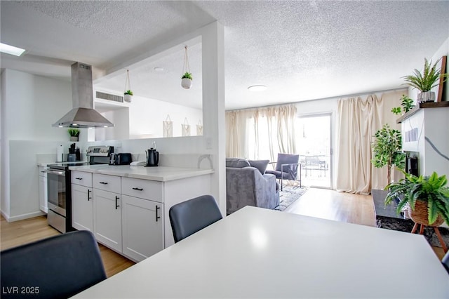 6301 Garwood Ave, Las Vegas, NV 89107 - kitchen with stainless steel electric range oven, island range hood, a textured ceiling, open shelves, and light wood finished floors