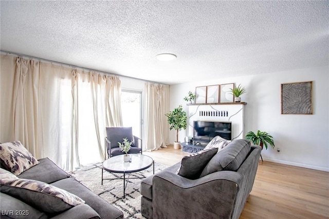 6301 Garwood Ave, Las Vegas, NV 89107 - living area featuring wood finished floors, a glass covered fireplace, baseboards, and a textured ceiling