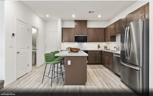6740 Nimbus Ave Lot 10, Las Vegas, NV 89130 - kitchen featuring stainless steel appliances, a breakfast bar, backsplash, a kitchen island, and light wood finished floors