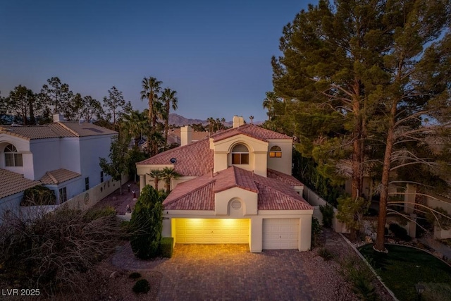 2104 Inverness Dr, Henderson, NV 89074 - mediterranean / spanish home with stucco siding, decorative driveway, an attached garage, a tiled roof, and a chimney