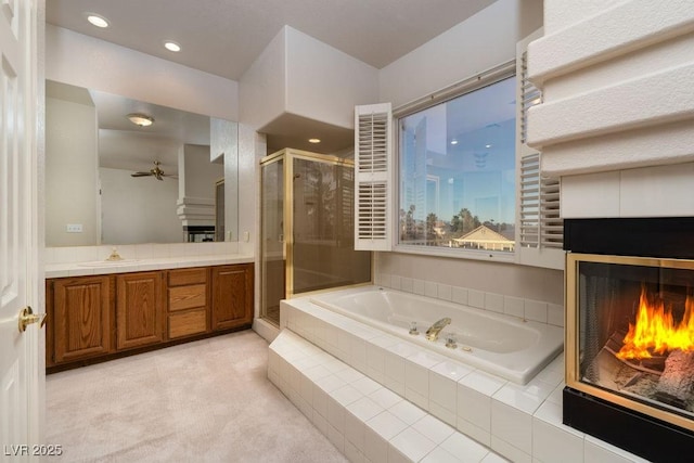2104 Inverness Dr, Henderson, NV 89074 - bathroom with a lit fireplace, a shower stall, a garden tub, vanity, and ceiling fan