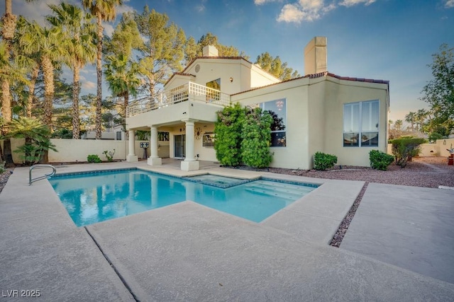 2104 Inverness Dr, Henderson, NV 89074 - rear view of house with a balcony, a patio, stucco siding, a chimney, and a pool with connected hot tub