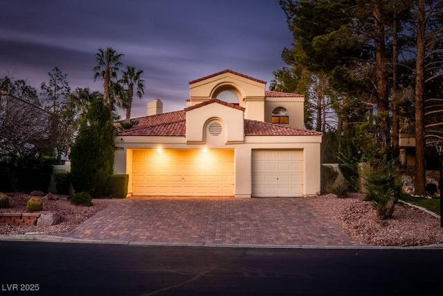 2104 Inverness Dr, Henderson, NV 89074 - mediterranean / spanish-style house with decorative driveway, an attached garage, stucco siding, a tile roof, and a chimney