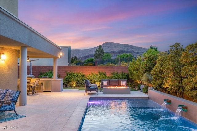 10482 Calico Terrace Ave, Las Vegas, NV 89135 - pool at dusk with a mountain view, an outdoor living space with a fire pit, and a patio