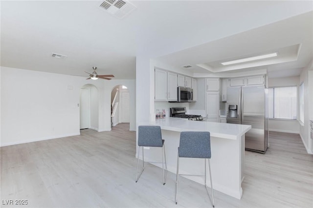 92 Sea Holly Way, Henderson, NV 89074 - kitchen with appliances with stainless steel finishes, arched walkways, a peninsula, a breakfast bar area, and light countertops