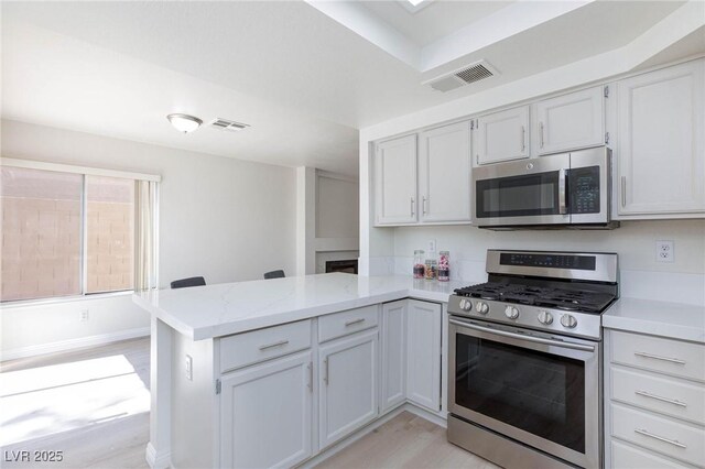 92 Sea Holly Way, Henderson, NV 89074 - kitchen with stainless steel appliances, a peninsula, and light wood-style flooring