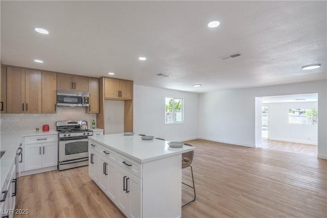 5279 Consul Ave, Las Vegas, NV 89142 - kitchen with stainless steel appliances, a breakfast bar, decorative backsplash, baseboards, and recessed lighting
