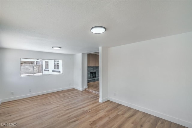 5279 Consul Ave, Las Vegas, NV 89142 - unfurnished room with baseboards, light wood finished floors, a textured ceiling, and a brick fireplace