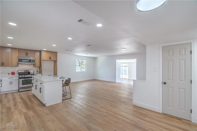 5279 Consul Ave, Las Vegas, NV 89142 - kitchen featuring appliances with stainless steel finishes, baseboards, a kitchen breakfast bar, light wood-type flooring, and light countertops