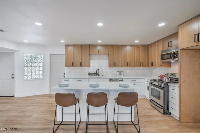 5279 Consul Ave, Las Vegas, NV 89142 - kitchen featuring stainless steel appliances, a sink, a kitchen bar, light countertops, and a kitchen island
