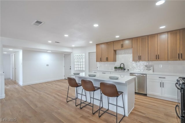 5279 Consul Ave, Las Vegas, NV 89142 - kitchen with dishwasher, a kitchen bar, light countertops, a sink, and a center island