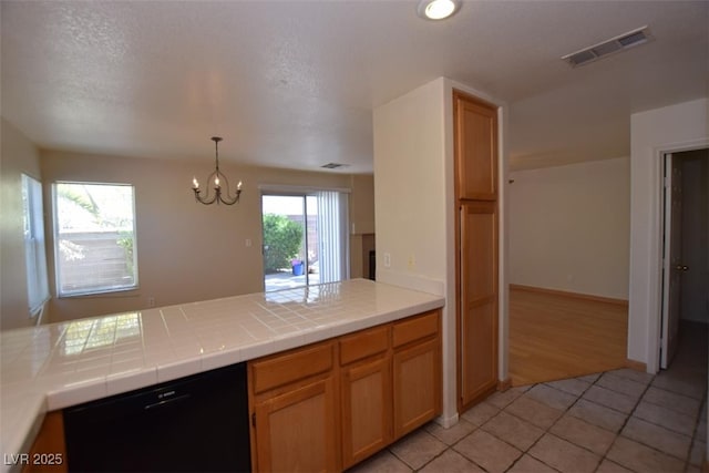1220 Padre Serra Ln, Las Vegas, NV 89134 - kitchen with a peninsula, light tile patterned floors, a chandelier, dishwasher, and tile counters