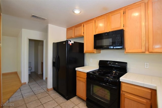 1220 Padre Serra Ln, Las Vegas, NV 89134 - kitchen with black appliances, tile counters, light tile patterned floors, baseboards, and light brown cabinets