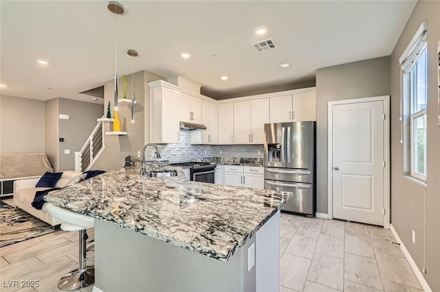 2806 Calle Cadiz, Henderson, NV 89044 - kitchen with stainless steel appliances, a sink, a peninsula, under cabinet range hood, and light stone counters