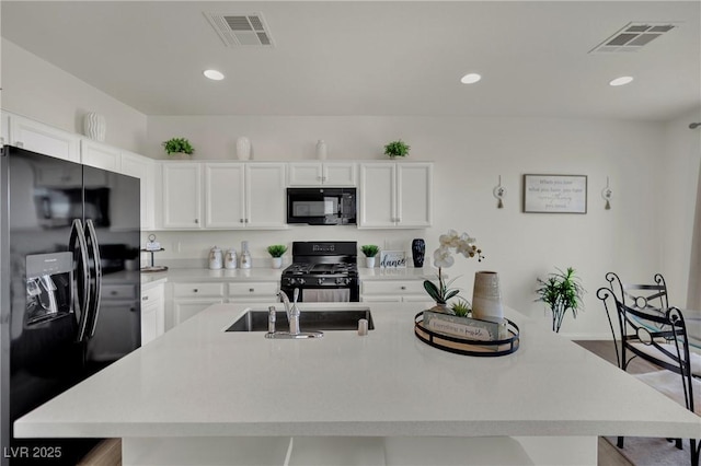 10345 Zebra Swallowtail St, Las Vegas, NV 89141 - kitchen featuring black appliances, a sink, light countertops, a kitchen island with sink, and white cabinets
