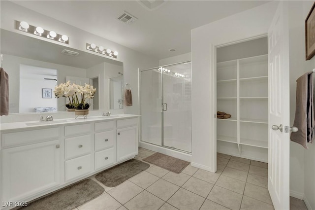 10345 Zebra Swallowtail St, Las Vegas, NV 89141 - bathroom featuring double vanity, a stall shower, tile patterned floors, a spacious closet, and baseboards