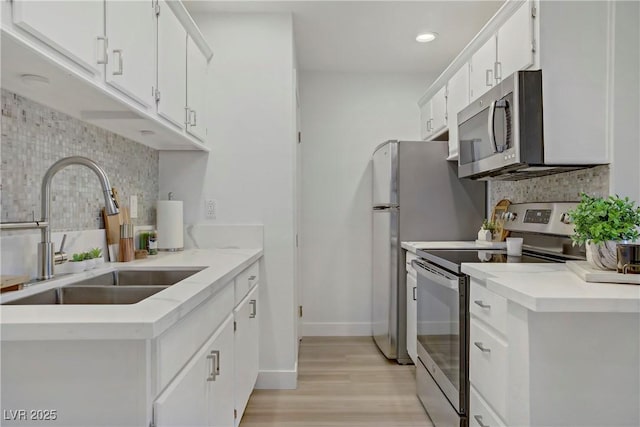 5171 Lindell Rd Unit 201, Las Vegas, NV 89118 - kitchen with appliances with stainless steel finishes, a sink, backsplash, light wood-style floors, and white cabinetry
