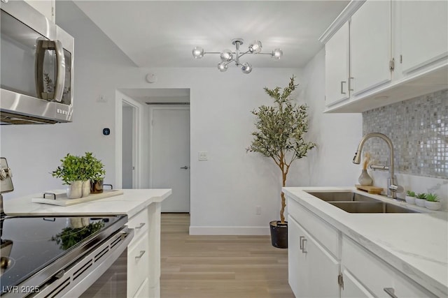 5171 Lindell Rd Unit 201, Las Vegas, NV 89118 - kitchen featuring appliances with stainless steel finishes, a sink, tasteful backsplash, light wood finished floors, and baseboards