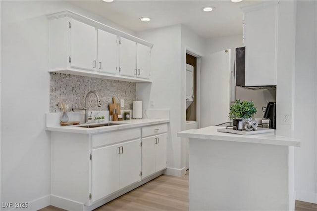 5171 Lindell Rd Unit 201, Las Vegas, NV 89118 - kitchen with a sink, white cabinetry, decorative backsplash, light wood-type flooring, and light countertops