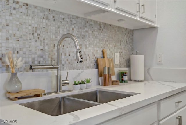 5171 Lindell Rd Unit 201, Las Vegas, NV 89118 - kitchen with a sink, decorative backsplash, white cabinets, and light stone countertops