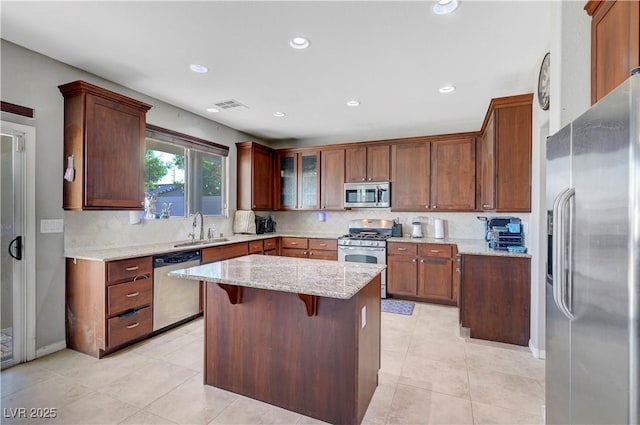 405 Prairie Moon Ave, North Las Vegas, NV 89084 - kitchen featuring appliances with stainless steel finishes, a sink, light stone counters, backsplash, and a kitchen island
