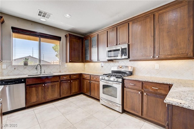 405 Prairie Moon Ave, North Las Vegas, NV 89084 - kitchen featuring stainless steel appliances, light stone counters, backsplash, light tile patterned floors, and glass insert cabinets