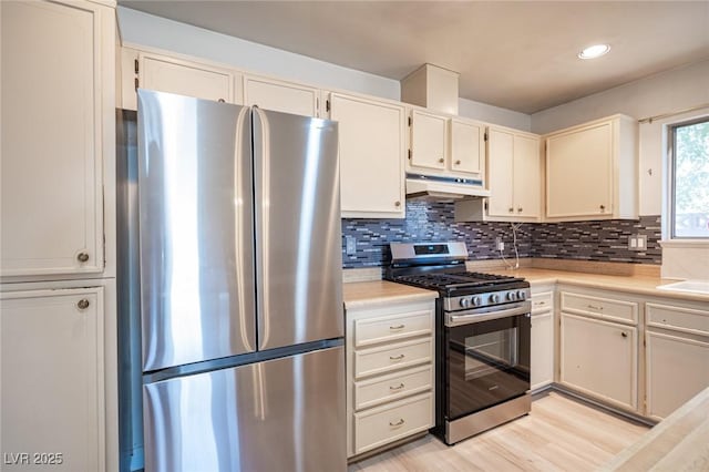 4409 Rosebank Cir, Las Vegas, NV 89108 - kitchen with stainless steel appliances, light countertops, tasteful backsplash, under cabinet range hood, and light wood finished floors