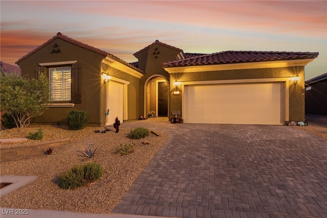 977 Majestic Vw, Mesquite, NV 89034 - mediterranean / spanish house featuring a garage, stucco siding, a tiled roof, and decorative driveway