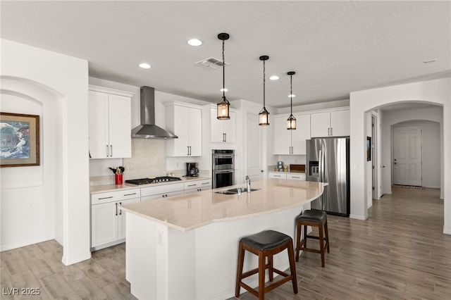 977 Majestic Vw, Mesquite, NV 89034 - kitchen featuring stainless steel appliances, wall chimney range hood, recessed lighting, arched walkways, and white cabinetry