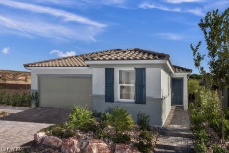 739 Wild Highlands Ln, Henderson, NV 89015 - mediterranean / spanish house featuring a garage, decorative driveway, stucco siding, and a tile roof