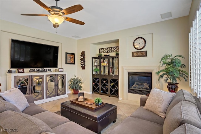 6440 Bristlebird St, North Las Vegas, NV 89084 - living area featuring tile patterned flooring, a ceiling fan, a glass covered fireplace, and baseboards