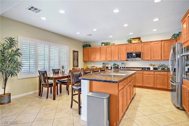 6440 Bristlebird St, North Las Vegas, NV 89084 - kitchen with stainless steel appliances, recessed lighting, light tile patterned flooring, an island with sink, and dark stone counters