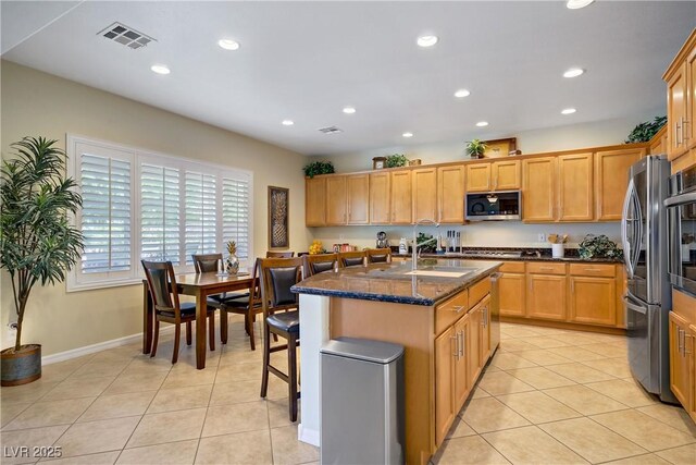 6440 Bristlebird St, North Las Vegas, NV 89084 - kitchen featuring appliances with stainless steel finishes, recessed lighting, a center island with sink, light tile patterned floors, and dark stone counters