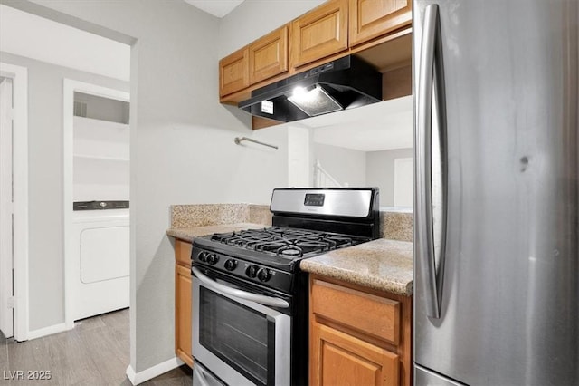 6445 Ironbark Ln, Las Vegas, NV 89107 - kitchen with stainless steel appliances, under cabinet range hood, washer / clothes dryer, wood finished floors, and light stone countertops