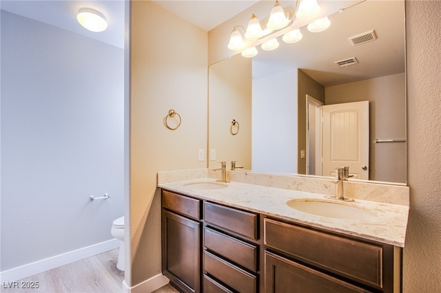 2369 Via Barranca St, Henderson, NV 89044 - bathroom with double vanity, toilet, wood finished floors, and baseboards