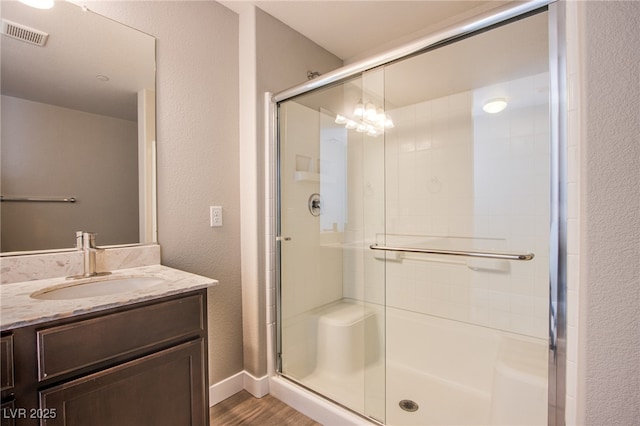 2369 Via Barranca St, Henderson, NV 89044 - bathroom featuring a stall shower, vanity, wood finished floors, a textured wall, and baseboards