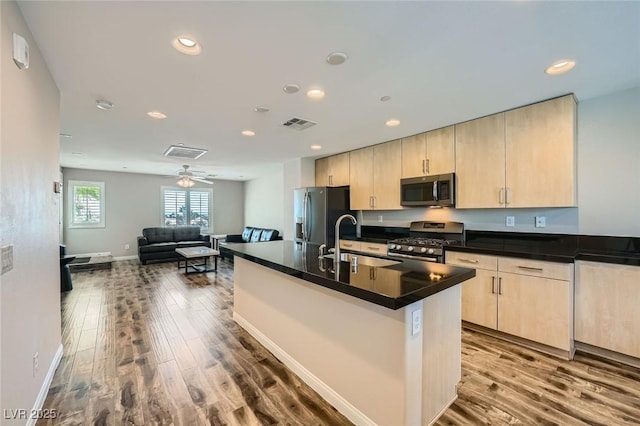9050 W Tropicana Ave Unit 1015, Las Vegas, NV 89147 - kitchen featuring appliances with stainless steel finishes, a sink, light brown cabinets, dark countertops, and dark wood-style flooring