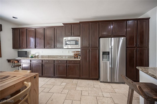 7538 Mustang St, Las Vegas, NV 89131 - kitchen featuring stainless steel appliances, stone tile floors, dark brown cabinets, and light stone counters