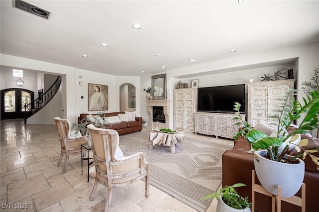 7538 Mustang St, Las Vegas, NV 89131 - living room with recessed lighting, a glass covered fireplace, stone tile flooring, french doors, and arched walkways