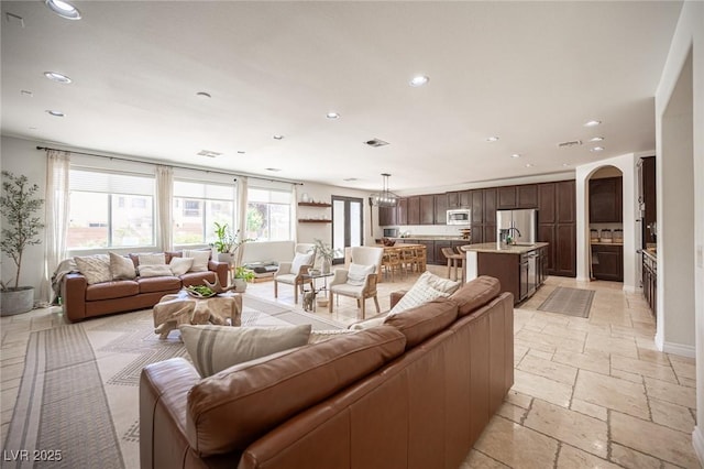 7538 Mustang St, Las Vegas, NV 89131 - living area featuring recessed lighting, arched walkways, stone tile floors, a chandelier, and baseboards