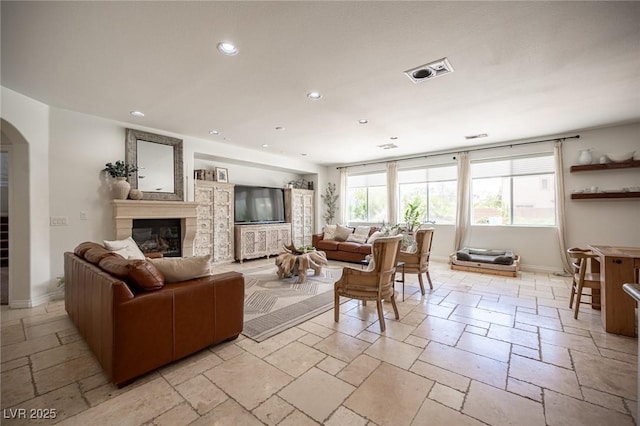 7538 Mustang St, Las Vegas, NV 89131 - living room with recessed lighting, stone tile floors, arched walkways, baseboards, and a large fireplace
