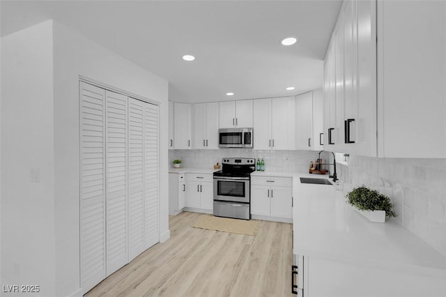 1115 W Nelson Ave, North Las Vegas, NV 89030 - kitchen with stainless steel appliances, a sink, light countertops, backsplash, and light wood-style floors
