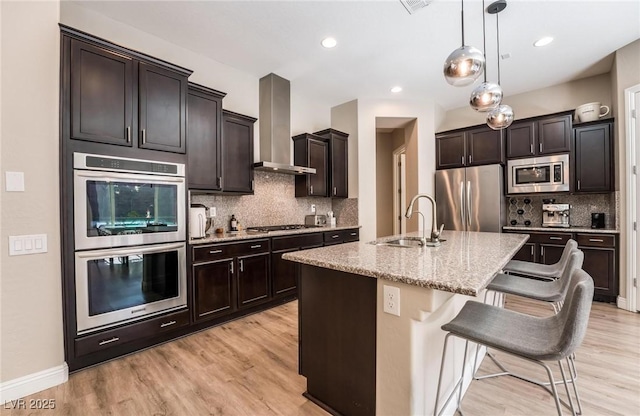 2896 Grande Arch St, Henderson, NV 89044 - kitchen with appliances with stainless steel finishes, wall chimney exhaust hood, a sink, light stone countertops, and backsplash