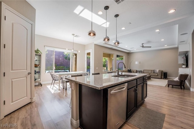 2896 Grande Arch St, Henderson, NV 89044 - kitchen featuring a sink, light wood-style flooring, a raised ceiling, stainless steel dishwasher, and light stone countertops