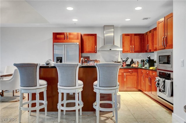 4525 Dean Martin Dr Unit 2109, Las Vegas, NV 89103 - kitchen with built in appliances, wall chimney range hood, a breakfast bar, dark countertops, and recessed lighting
