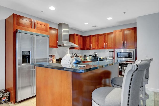 4525 Dean Martin Dr Unit 2109, Las Vegas, NV 89103 - kitchen featuring wall chimney exhaust hood, built in appliances, a kitchen island, a kitchen bar, and recessed lighting