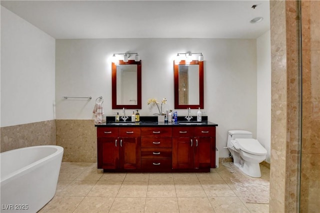 4525 Dean Martin Dr Unit 2109, Las Vegas, NV 89103 - bathroom with a freestanding bath, double vanity, wainscoting, tile patterned flooring, and toilet